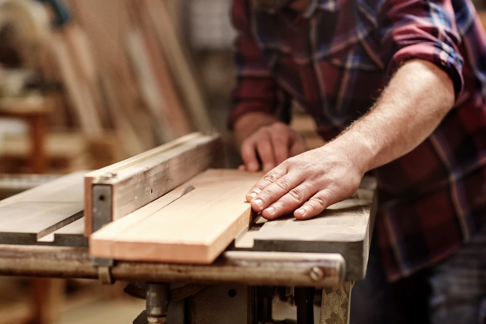 Atelier de menuiserie intérieur avec artisan en chemise à carreaux travaillant le bois