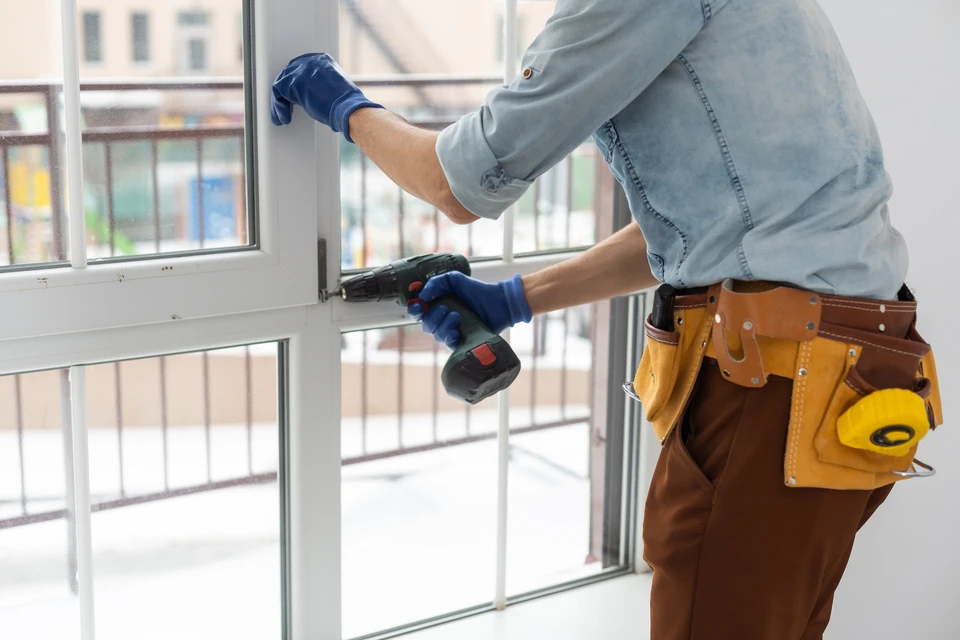 Le travailleur installe et vérifie la fenêtre dans la maison