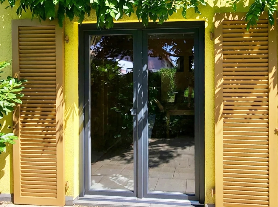 Façade extérieure d'une maison avec double porte-fenêtre en aluminium anthracite à deux vantaux vitrés pleine hauteur