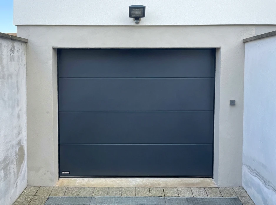 Porte de garage sectionnelle anthracite (RAL 7016), lisse sans nervures, montage en applique dans une façade enduite blanche