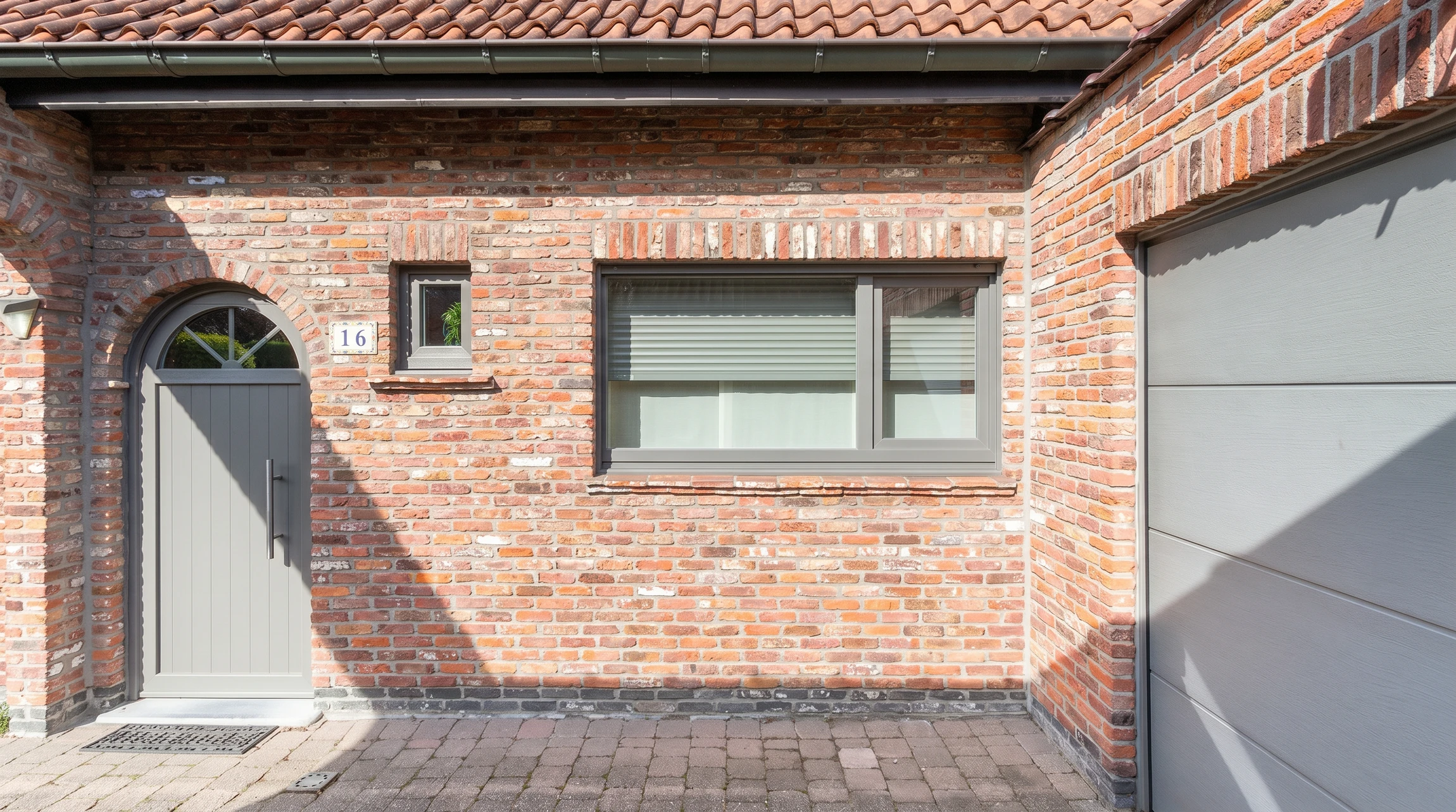 Entrée extérieure de maison moderne avec porte d'entrée contemporaine noire à panneau vitré supérieur et poignée métallique dorée