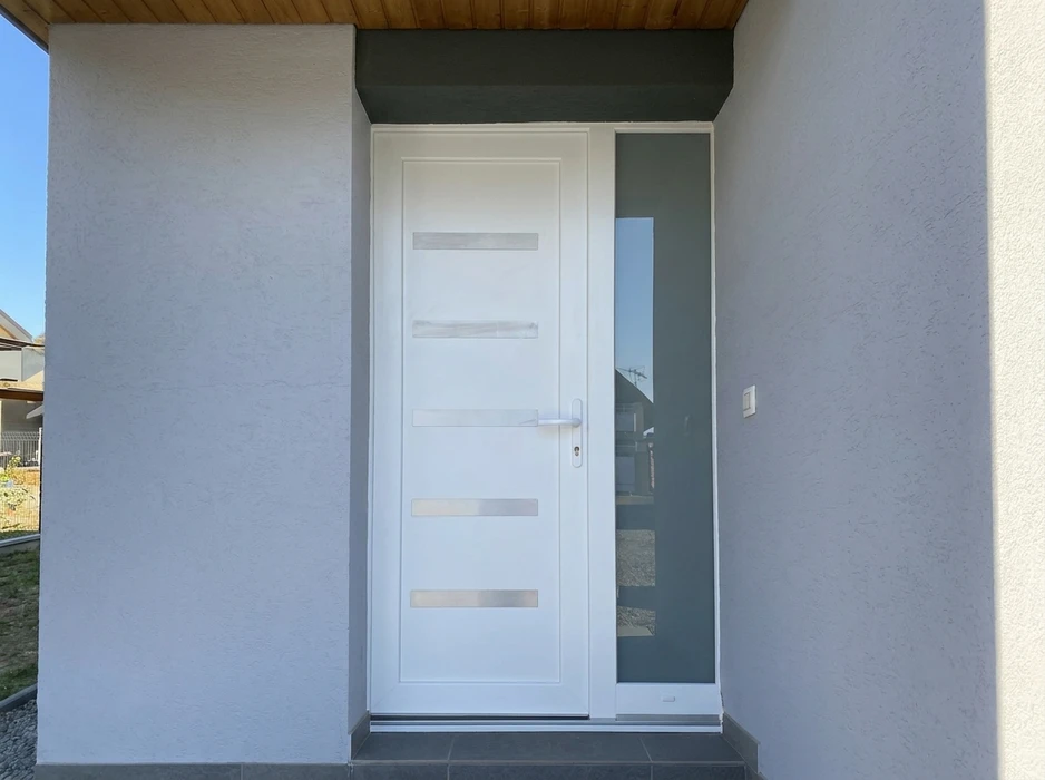 Entrée d'une maison de style provençal, façade en enduit rose, porte d'entrée moderne gris anthracite avec vitrage dépoli intégré, encadrement en pierre naturelle