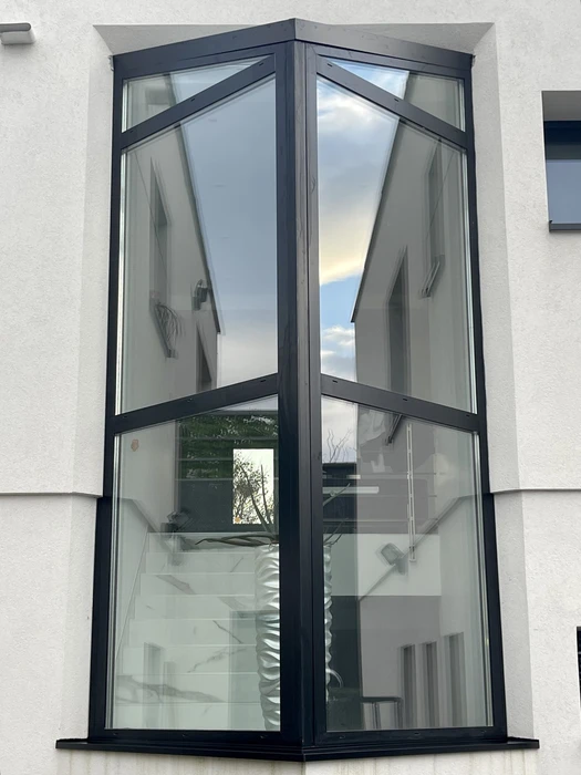 Entrée extérieure d'une maison moderne avec une porte d'entrée aluminium blanche à un vantail, équipée d'une poignée en aluminium anodisé blanc et d'une serrure centrale