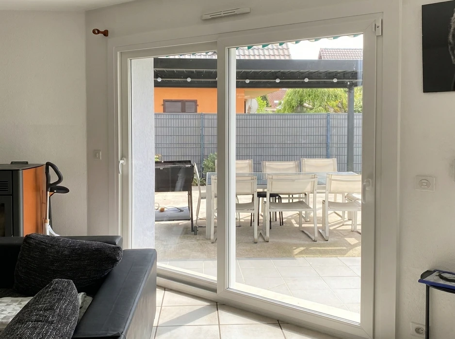 Vue intérieure d'une fenêtre de toit type Velux, cadre PVC blanc, encaissée dans un puits de lumière habillé de lambris en pin naturel verni