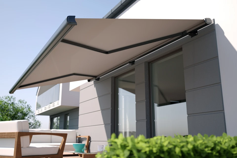 Homme en pull gris utilisant une perceuse-visseuse sans fil pour fixer un élément au mur dans un intérieur résidentiel moderne avec étagères en arrière-plan