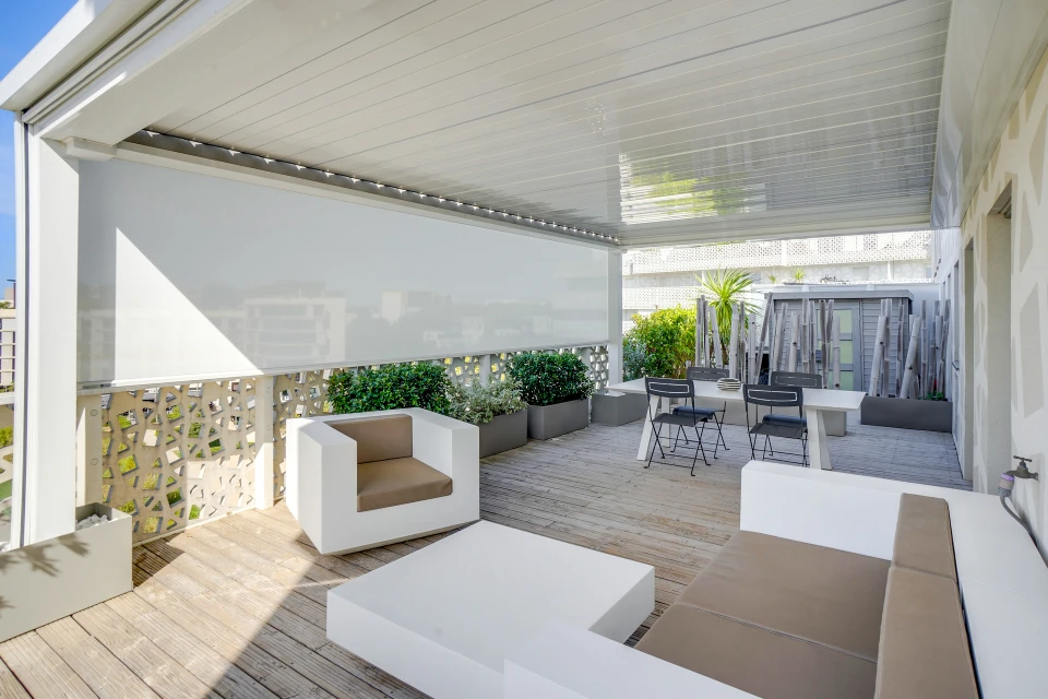 Baie vitrée coulissante trois vantaux, vue depuis l'extérieur, donnant sur une terrasse avec salon de jardin